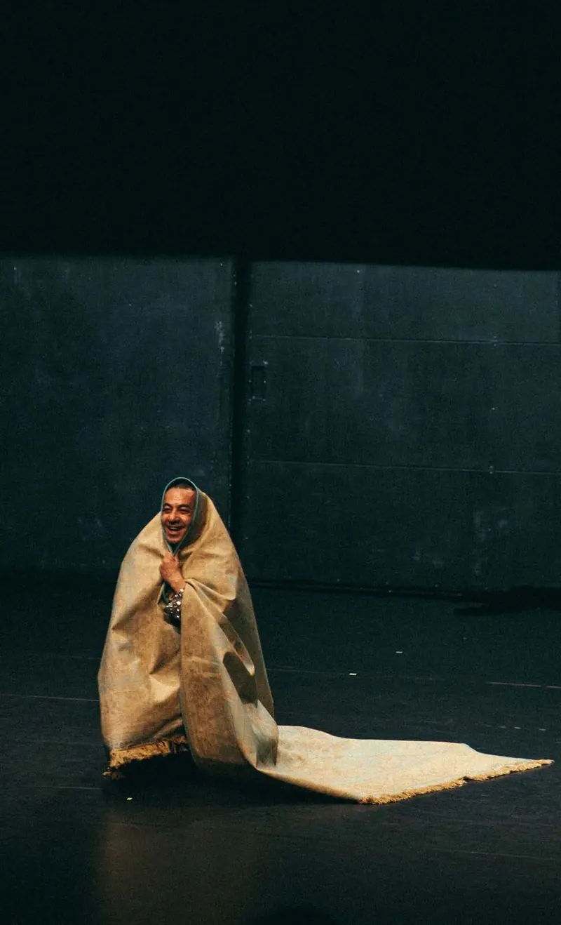 Performer wrapped in a rug on stage, Ma recréation - Abou Lagraa, Les Plateaux Sauvages, Paris, 2026. Photo by Iheb Fehri